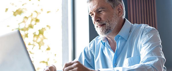 Smiling older man reading a tablet
